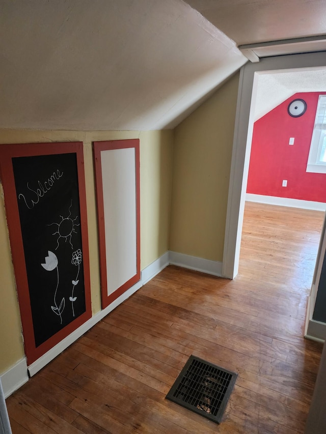 additional living space with hardwood / wood-style floors and lofted ceiling