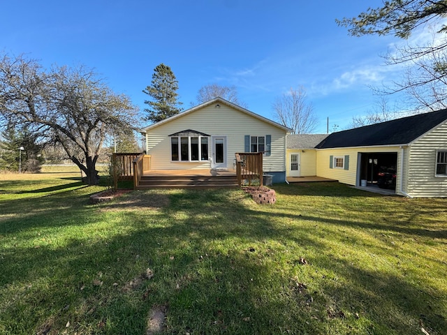 rear view of property featuring a garage, a deck, and a yard