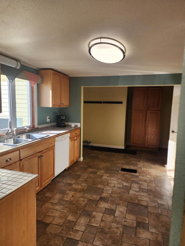 kitchen with dishwasher, a textured ceiling, tile countertops, and sink