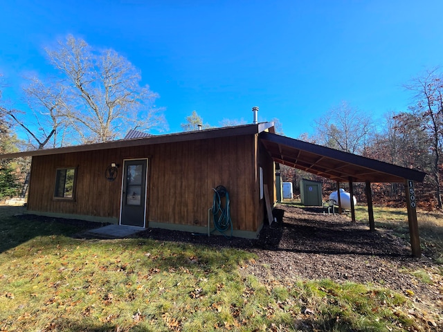 rear view of house featuring a lawn and a carport