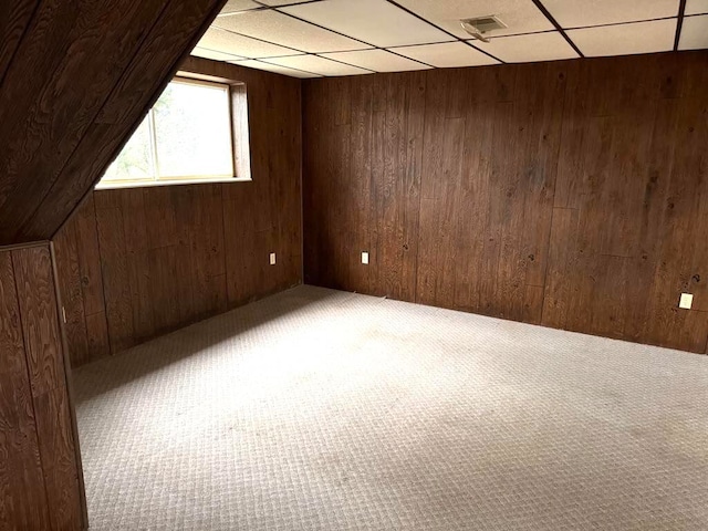 carpeted empty room featuring a paneled ceiling and wooden walls