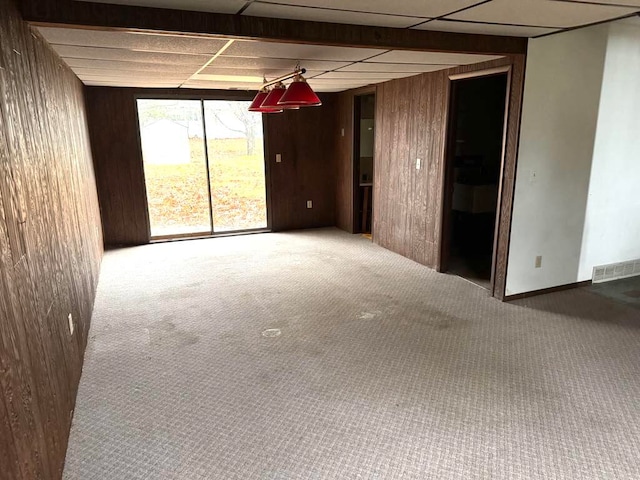 spare room featuring carpet flooring and wood walls