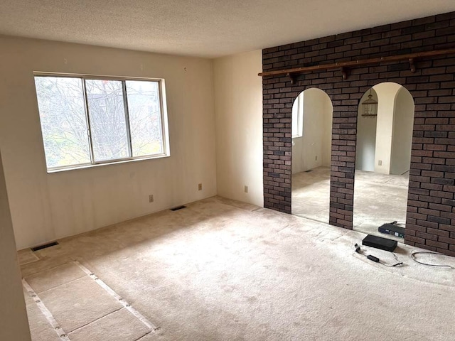 empty room with light colored carpet and a textured ceiling