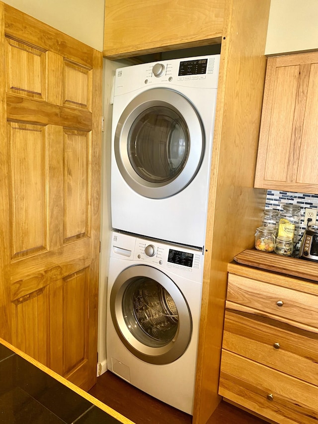 washroom with dark hardwood / wood-style floors and stacked washer / drying machine