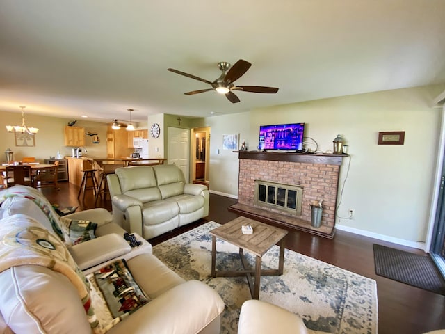 living room featuring dark hardwood / wood-style floors, ceiling fan with notable chandelier, and a brick fireplace