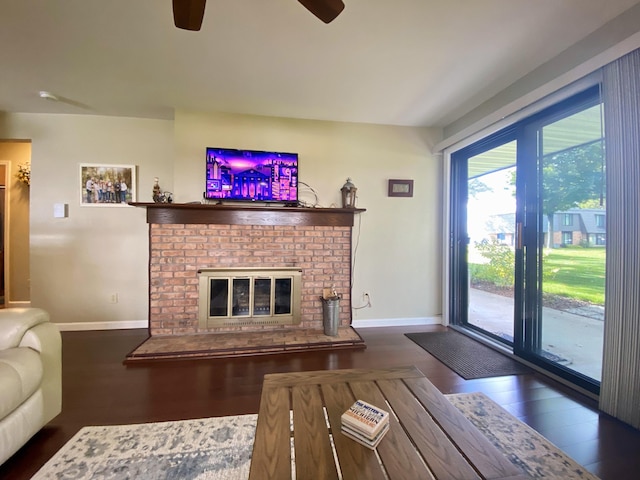 living room featuring ceiling fan, dark hardwood / wood-style floors, and a brick fireplace