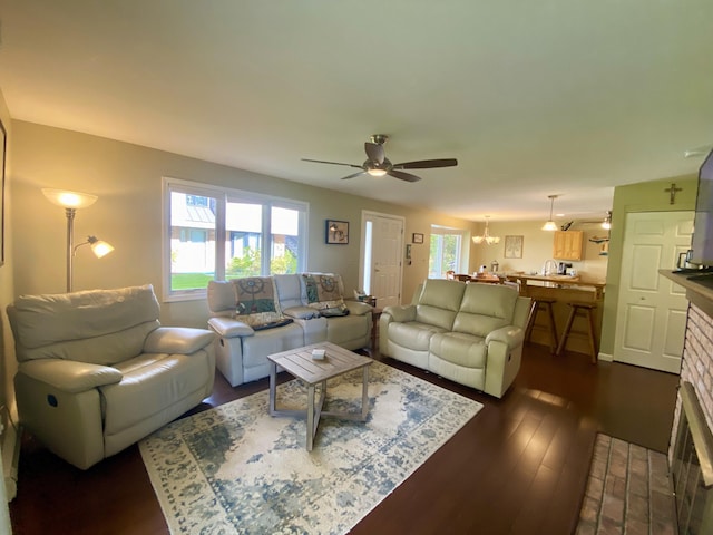 living room featuring a brick fireplace, ceiling fan, and dark wood-type flooring