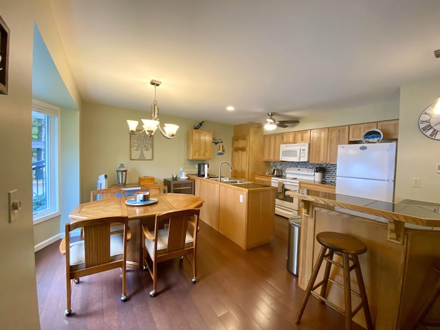 dining space featuring sink, ceiling fan with notable chandelier, and dark hardwood / wood-style floors