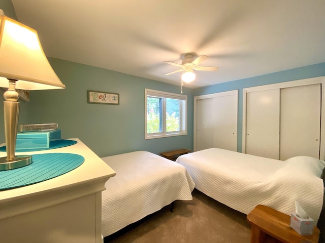 carpeted bedroom featuring multiple closets and ceiling fan