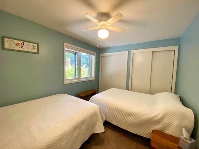 carpeted bedroom with ceiling fan and multiple closets