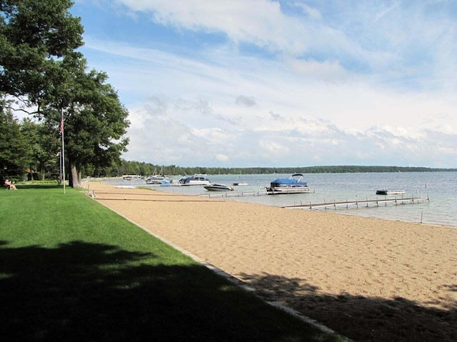 surrounding community with a boat dock, a water view, and a yard