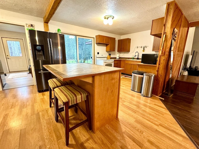 kitchen featuring stainless steel fridge, light wood-type flooring, white range with electric stovetop, sink, and tile countertops