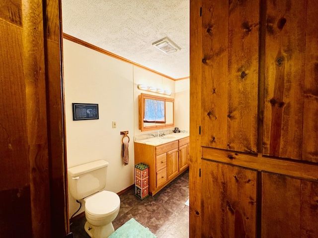 bathroom with toilet, vanity, a textured ceiling, and ornamental molding