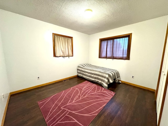 bedroom featuring dark hardwood / wood-style flooring and a textured ceiling