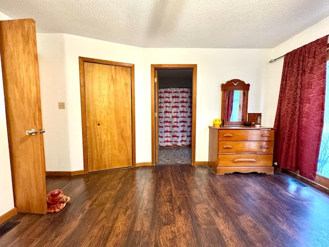 unfurnished bedroom featuring a textured ceiling, dark hardwood / wood-style floors, and multiple windows