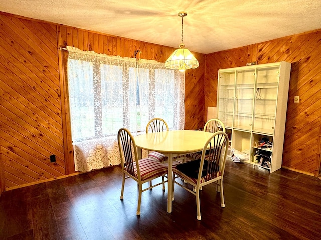 dining room with a notable chandelier, dark hardwood / wood-style flooring, and wooden walls