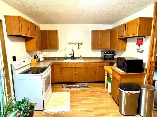 kitchen featuring a textured ceiling, light hardwood / wood-style flooring, white range with electric cooktop, and sink