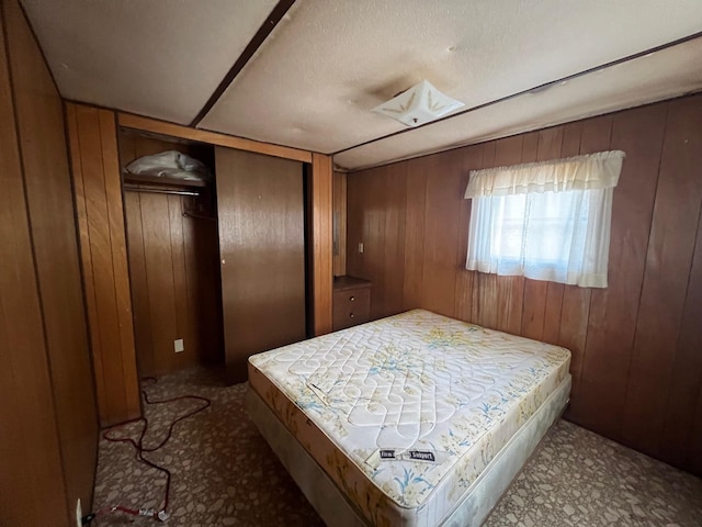 bedroom featuring wood walls and a textured ceiling