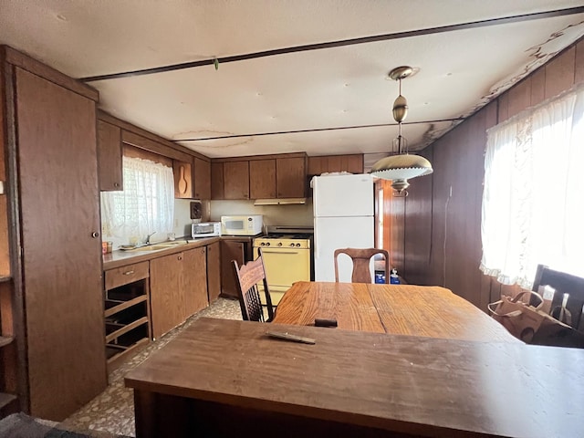 kitchen with wooden walls, hanging light fixtures, and white appliances