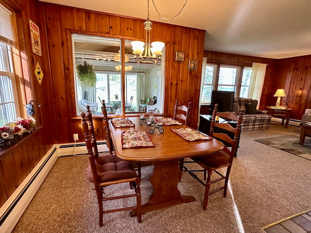 dining room featuring a chandelier, wooden walls, carpet floors, and a healthy amount of sunlight