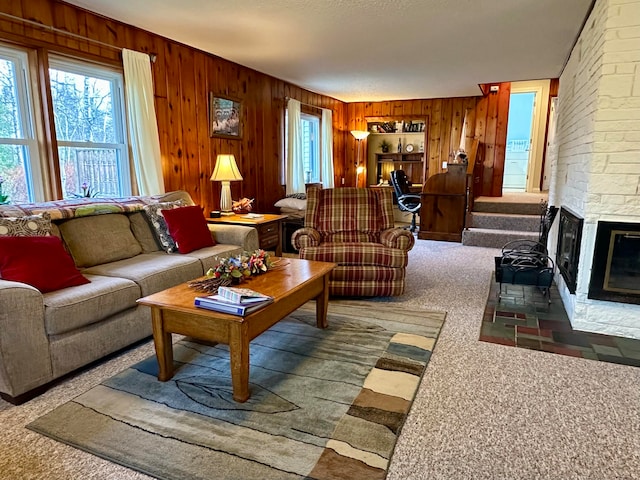 carpeted living room featuring a fireplace, a textured ceiling, and wooden walls