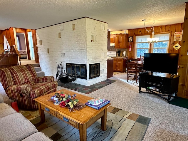 living room with wood walls, light carpet, a stone fireplace, a textured ceiling, and a chandelier