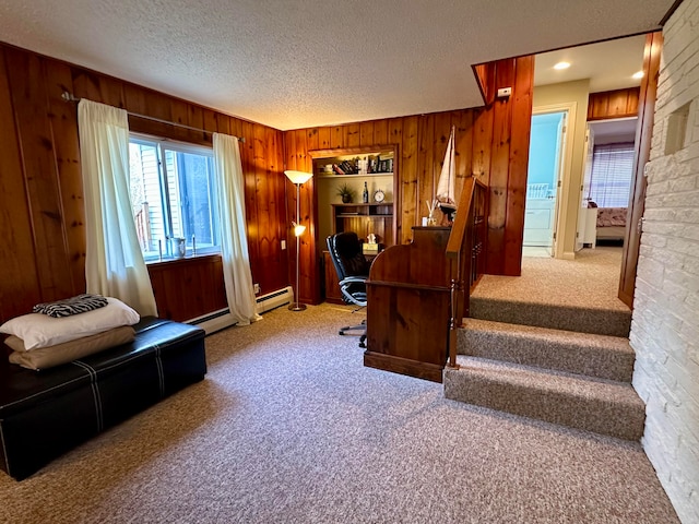 carpeted office space featuring wood walls, a textured ceiling, and a baseboard heating unit