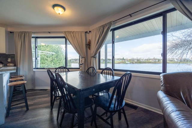 dining room with a water view and dark wood-type flooring