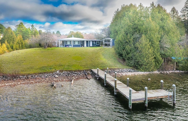 view of dock featuring a lawn and a water view