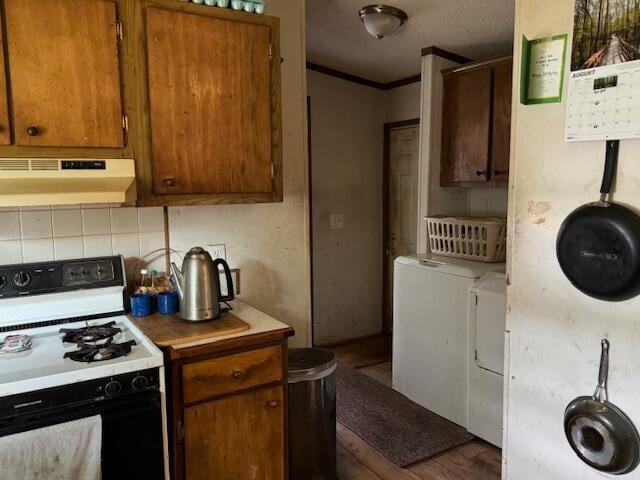 kitchen featuring white range, crown molding, dark hardwood / wood-style floors, extractor fan, and washing machine and clothes dryer