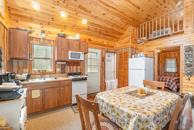 kitchen with white appliances, wooden ceiling, sink, wooden walls, and light colored carpet