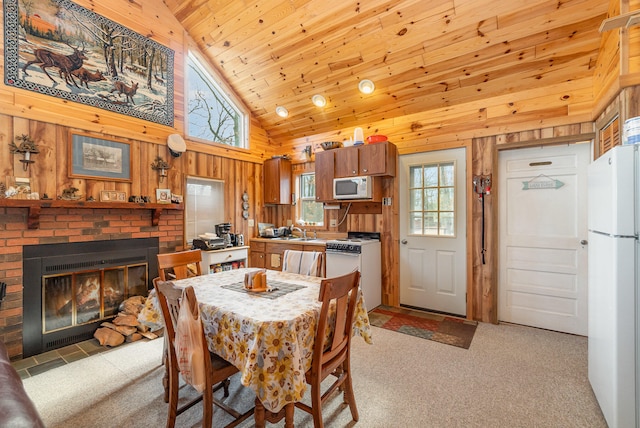 dining area with light carpet, a brick fireplace, wood ceiling, sink, and high vaulted ceiling