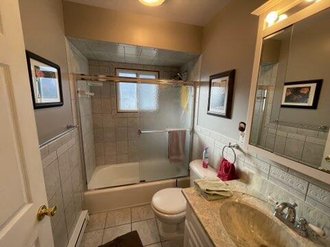 full bathroom with baseboard heating, enclosed tub / shower combo, tile patterned floors, toilet, and vanity