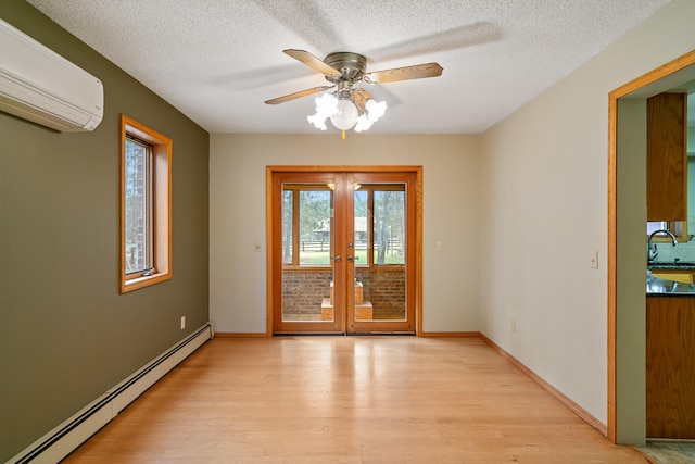 spare room with french doors, a textured ceiling, baseboard heating, light hardwood / wood-style floors, and a wall unit AC