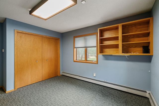 unfurnished bedroom featuring baseboard heating, a closet, carpet floors, and a textured ceiling