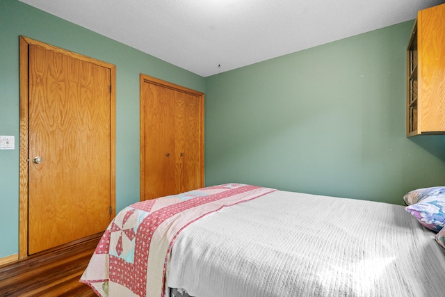 bedroom with dark hardwood / wood-style floors and a textured ceiling