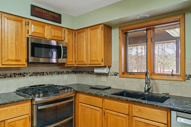 kitchen with backsplash, sink, stainless steel appliances, and dark stone counters