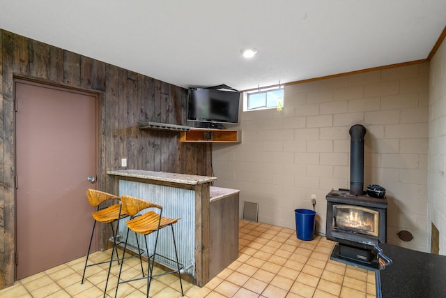 kitchen with kitchen peninsula, ornamental molding, a breakfast bar, dark brown cabinetry, and a wood stove