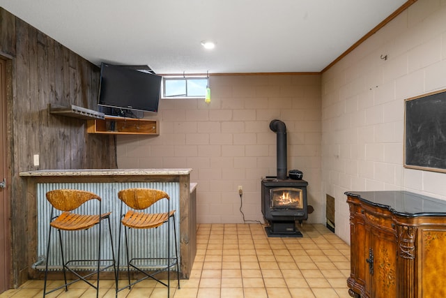 kitchen featuring a wood stove, light tile patterned floors, and ornamental molding