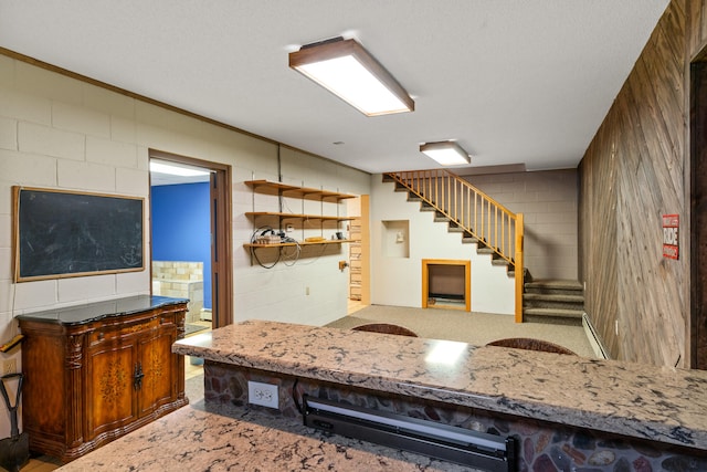 kitchen with a textured ceiling, wooden walls, and crown molding