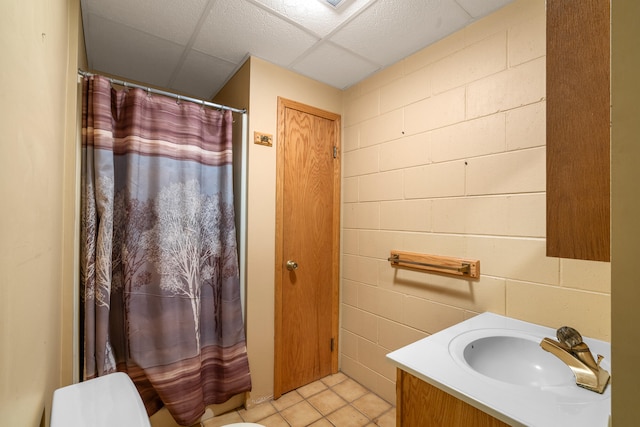 bathroom with a paneled ceiling, vanity, toilet, and tile patterned floors