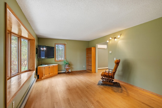 unfurnished room featuring an AC wall unit, light hardwood / wood-style floors, a textured ceiling, and a baseboard heating unit