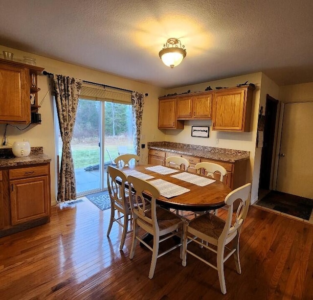 dining area with a textured ceiling and dark wood-type flooring