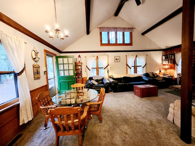 dining room featuring beamed ceiling, high vaulted ceiling, a chandelier, wooden walls, and dark carpet