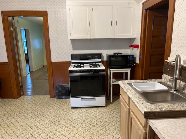 kitchen featuring white stove, white cabinetry, and sink