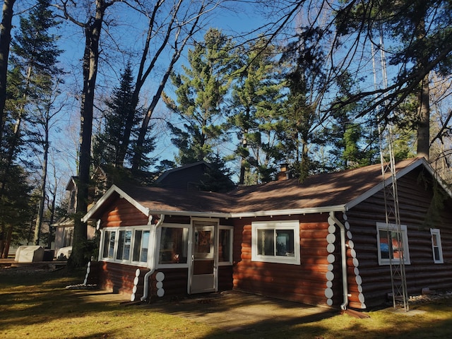 back of house featuring a sunroom and a lawn