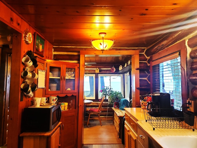 kitchen featuring pendant lighting, light hardwood / wood-style flooring, log walls, and wooden ceiling