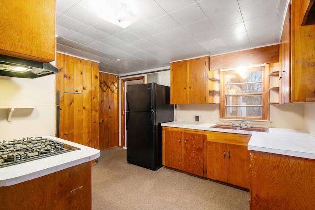 kitchen featuring black fridge, sink, custom range hood, and stainless steel gas stovetop