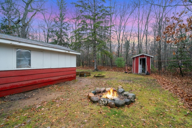 yard at dusk with a fire pit and a shed