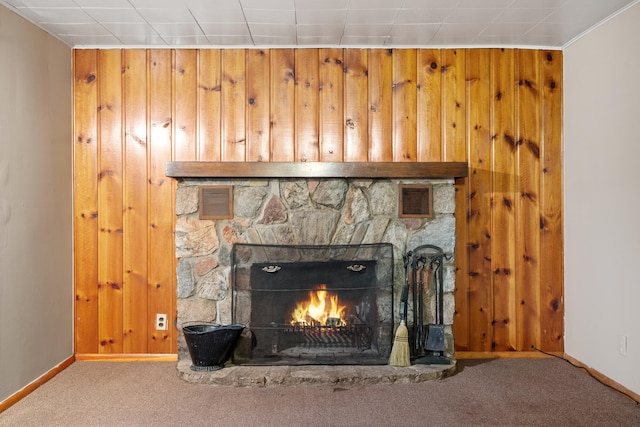 interior details featuring carpet, wood walls, a stone fireplace, and ornamental molding